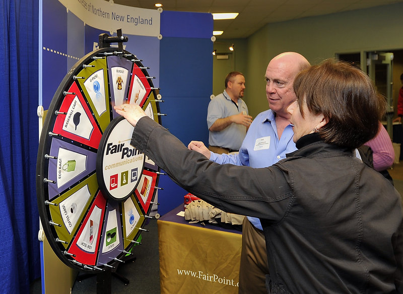 Chip Underhill, a marketing representative for FairPoint Communications, helps Deborah Fuller spin the prize wheel after talking about his company at the Greater Portland Business Expo at Holiday Inn By the Bay on Tuesday.