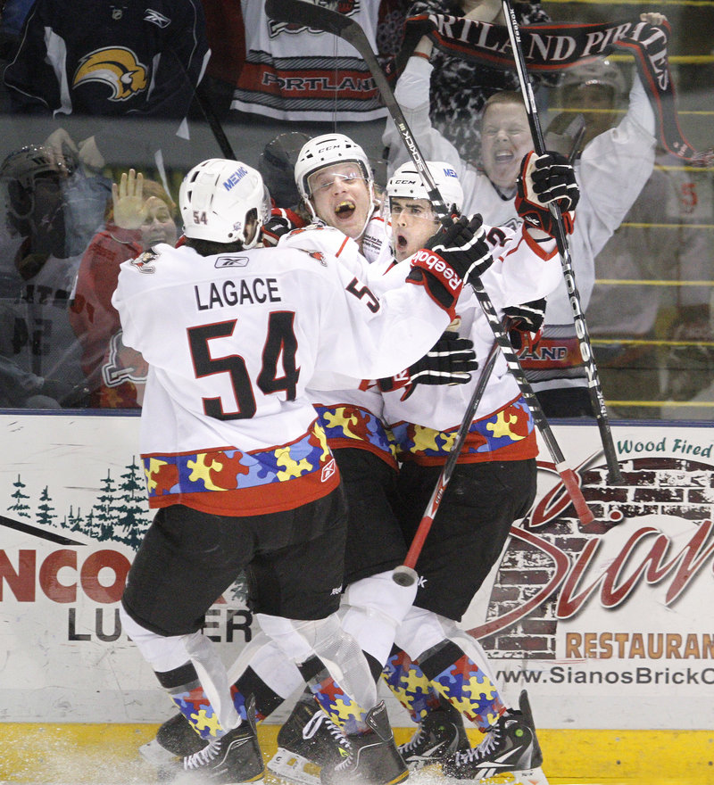 Derek Whitmore, right, celebrates with Jason Lagace, left, and Tim Conboy after his third-period goal gave Portland a 5-4 lead.