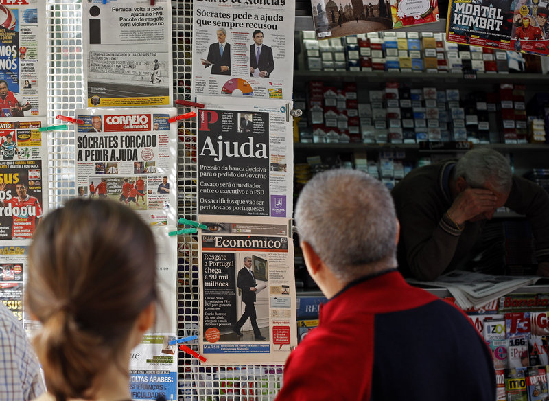 People in Lisbon, Portugal, look at newspapers’ front pages Thursday. Prime Minister Jose Socrates said late Wednesday that Portugal will ask for a bailout to relieve its crushing debt, joining Greece and Ireland in seeking outside help amid a bruising financial crisis.