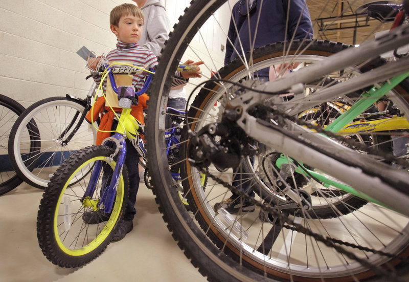 Gray Lindsay, 5, of Kennebunkport waits with his dad to buy a bicycle he picked out at the Bicycle Coalition of Maine Great Portland Bike Swap in Portland on Sunday.