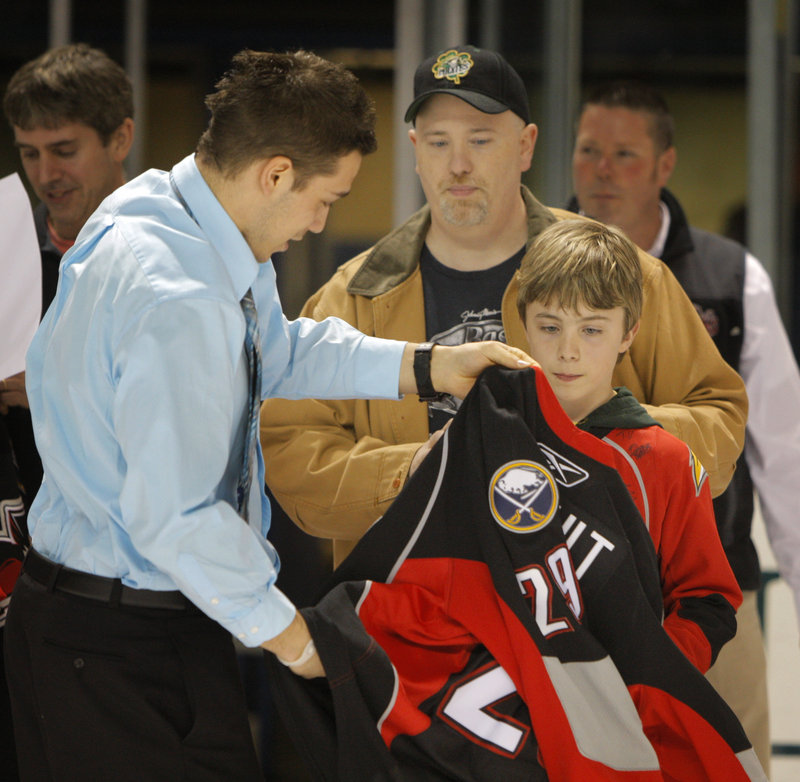 Pirates forward Maxime Legault gives his jersey to Dylan Fyler of Porter as Fyler's father, Bill, looks on.