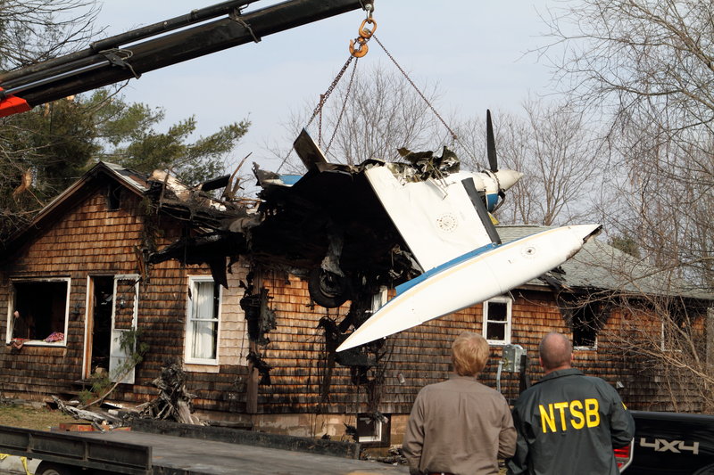 Crews remove the fuselage of the twin-engine Cessna 402 from the roof of the home at 235 Granite St. Extension in Biddeford on Monday. The plane landed on the house Sunday evening in a fiery crash that killed the pilot. No one was home at the time of the crash.