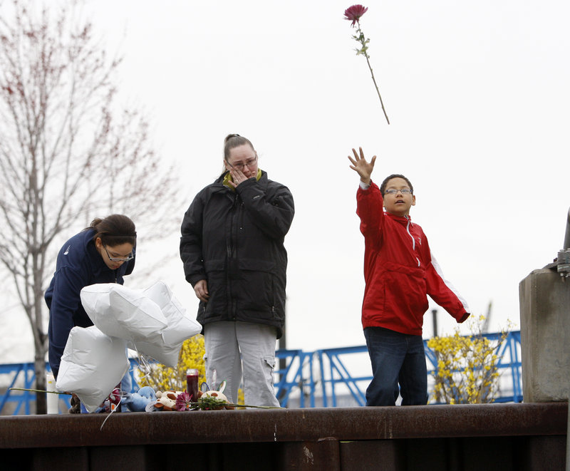 Demetrius Galloway, right, throws a flower into the Hudson River on Wednesday at a boat launch where a woman drove her minivan and four of her children into the water.