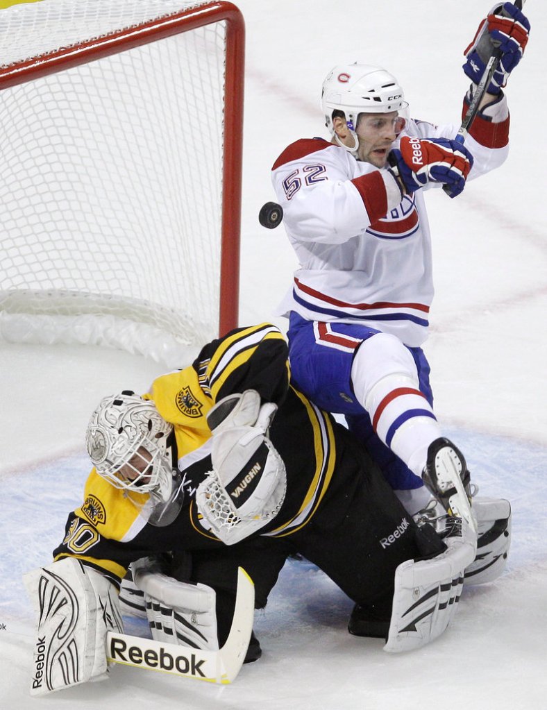 Bruins goalie Tim Thomas knocks away the puck as Canadiens left wing Mathieu Darche falls onto him in Montreal’s 2-0 playoff win Thursday night at Boston.
