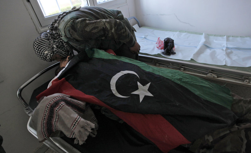 The body of Moftah Wanis el-Jazwi, a rebel fighter killed during clashes with troops loyal to Libyan leader Moammar Gadhafi, is wrapped with an opposition flag as a fellow soldier kisses him goodbye Saturday at a hospital in Ajdabiya.