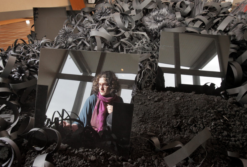 Artist Lauren Fensterstock is reflected in a Plexiglas panel that is part of her “Incidents of Garden Displacement” last week as she installs the sculptural garden made of black paper, charcoal and reflective squares at the Ogunquit Museum of American Art. The seaside museum in Ogunquit reopens for the season on May 1.