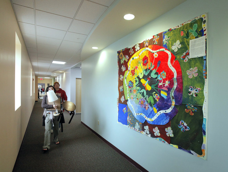 Allegra Hirsh, a counselor with Community Counseling Center, carries furnishings to her office Monday at the center’s new location at 165 Lancaster St. The wall art, called The Butterflies of Spring, was made by members of the Elderworks program.