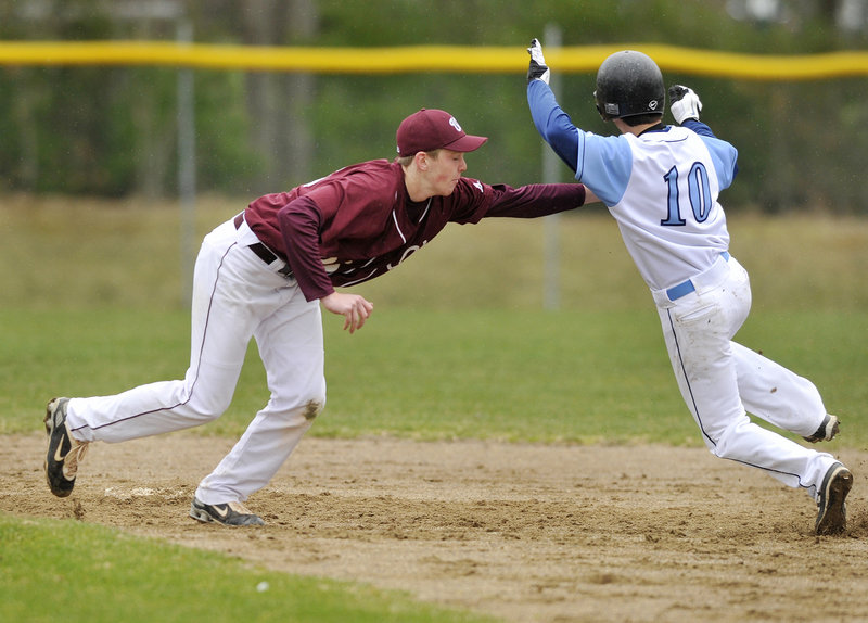 Windham's Cody Dube, left, tags out Westbrook's Joe Quinlan on a steal attempt in the bottom of the first inning Monday afternoon in Westbrook. The Blue Blazes opened with a 3-0 victory.