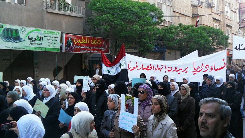 Syrian women carry a banner in Arabic that reads: “The women of Daraa want an end to the siege,” as they protest in Daraa, southwest of Damascus, on Monday, in this image made on a mobile phone and acquired by The Associated Press.