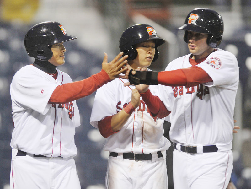 Three Sea Dogs, from left, Che-Hsuan Lin, Jon Hee and Alex Hassan, celebrate after scoring on a double by Tim Federowicz that highlighted a five-run seventh inning Tuesday night during Portland s 8-2 win over Binghamton.