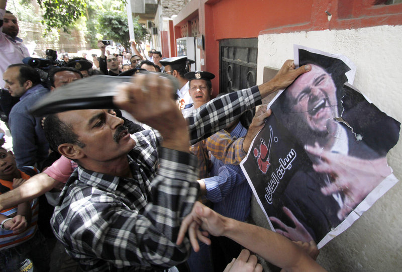 A Syrian man beats a poster of President Bashar al-Assad with a shoe during a protest Tuesday at the Syrian Embassy in Cairo, Egypt. Human rights groups say at least 35 people have died in the past two days in an onslaught by Syrian forces.