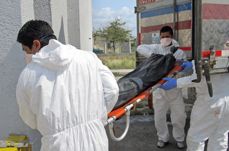 Employees unload a body from a refrigerated truck last week at the city morgue in Matamoros, Mexico. Families of those feared abducted and killed by the Zeta drug cartel have taped photocopied fliers of their loved ones to the walls of state forensic offices there, hoping the bodies can be identified.