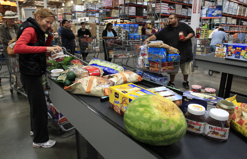 Shoppers load a conveyor belt at a checkout counter at Costco in Mountain View, Calif. Americans saw their incomes rise last month, but analysts say most of the extra money went toward covering higher prices for gas and food.