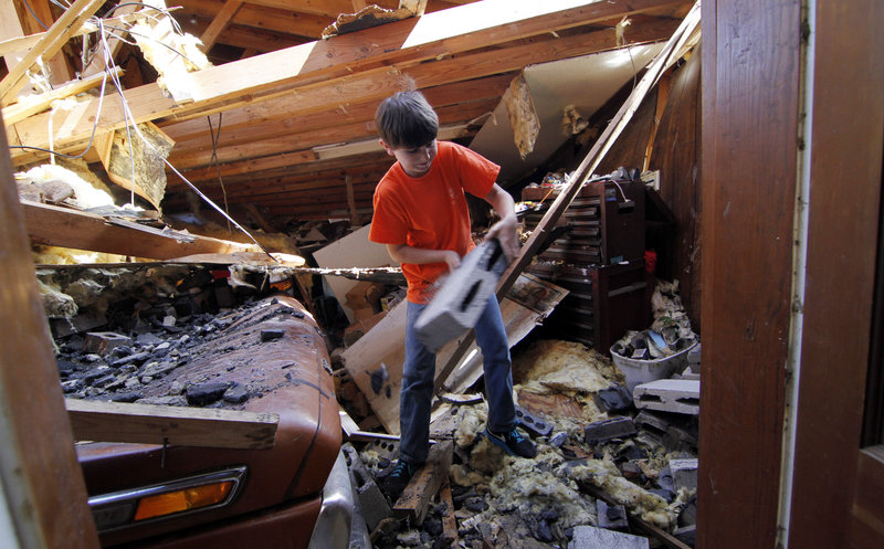 Bryton Frost, 10, tosses aside debris in his grandfather’s wrecked garage Friday in Hackleburg, Ala. Survivors of the deadliest tornado outbreak since the Great Depression endured blackouts and long lines for gas as they began digging what possessions they could find from the rubble.