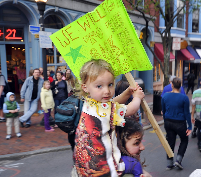 Two-year-old Sadie Catalogna waves a sign from her perch atop her mom, marcher Kristina Catalogna of Portland.