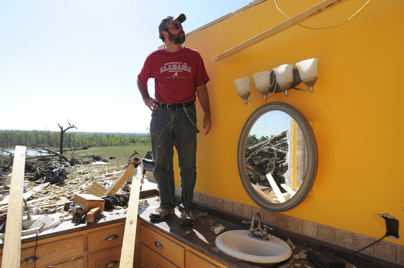 Allen Hamilton stands on the bathroom counter in the wreckage of his home Friday in Rainsville, Ala. Hamilton and his family survived a tornado Wednesday by taking refuge in a closet next to the bathroom.