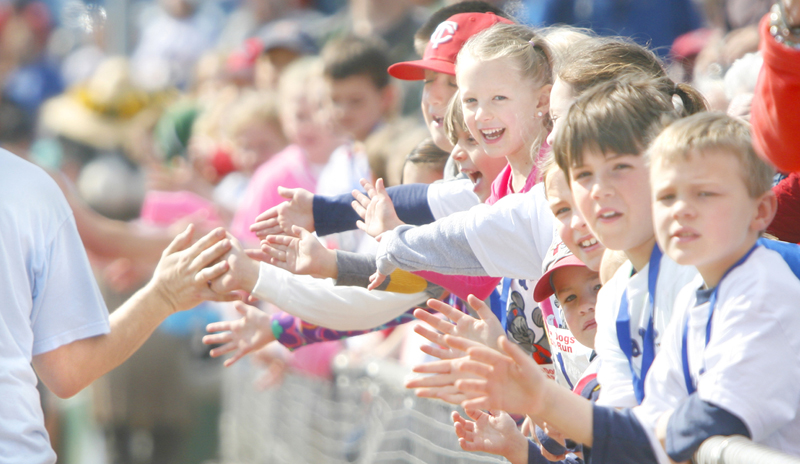 Kids slap hands with runners along the third-base line near the finish line at Hadlock Field during the Mothers' Day 5K sponsored by the Sea Dogs.