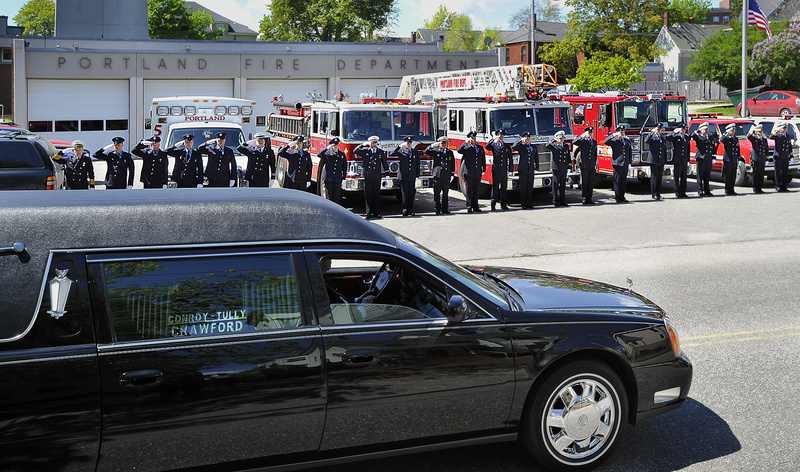 Firefighters salute Wednesday as the funeral procession for James P. Fox stops at the Bramhall Station on Congress Street. Fox, who had Down syndrome, was named the department’s honorary deputy chief in 2003.