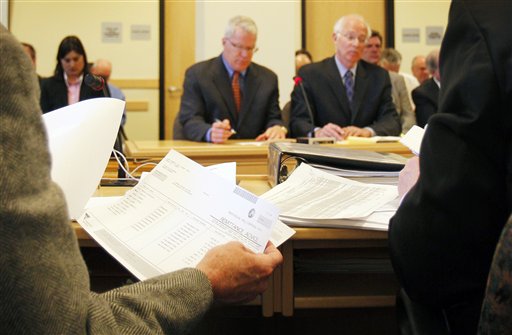 A member of the Legislature's Government Oversight Committee, reviews spending records during the questioning of Paul Violette, the former executive director of the Maine Turnpike Authority, Friday, April 15, 2011, in Augusta, Maine. Violette, in background at left, invoked his constitutional right against self-incrimination and refused to answer questions about the authority's spending practices. (AP Photo/Robert F. Bukaty)