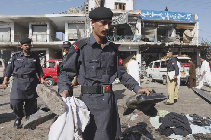 A soldier of the Pakistani paramilitary force collects the belongings of his colleagues after the bombing in Shabqadar near Peshawar today.