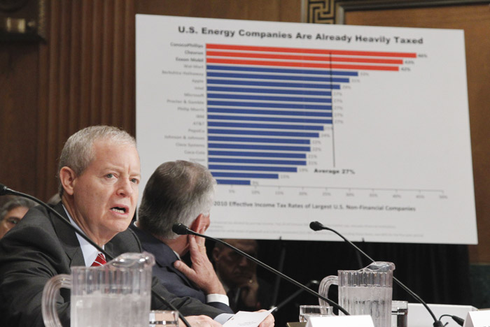 ConocoPhillips CEO James Mulva, left, speaks while ExxonMobil CEO Rex Tillerson looks at a chart on Capitol Hill today.