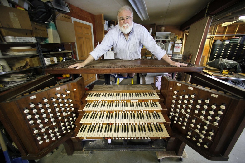 John Bishop, executive director of the Massachusetts-based Organ Clearing House, poses with the console of an 1846 Aeolian Skinner organ in Newcastle, Maine. The organ, which is being refurbished by Bishop, was donated by Trinity Wall Street to Johns Creek United Methodist Church in Georgia.