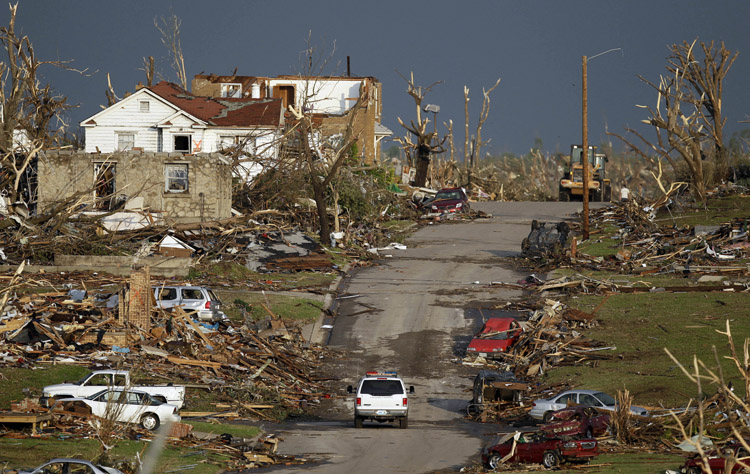 An emergency vehicle drives through a severely damaged neighborhood in Joplin, Mo., today.