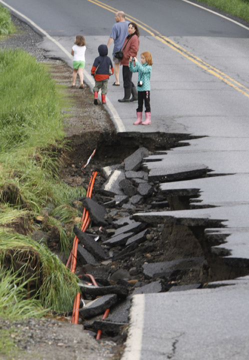 Residents look over a damaged road today in East Montpelier, Vt.