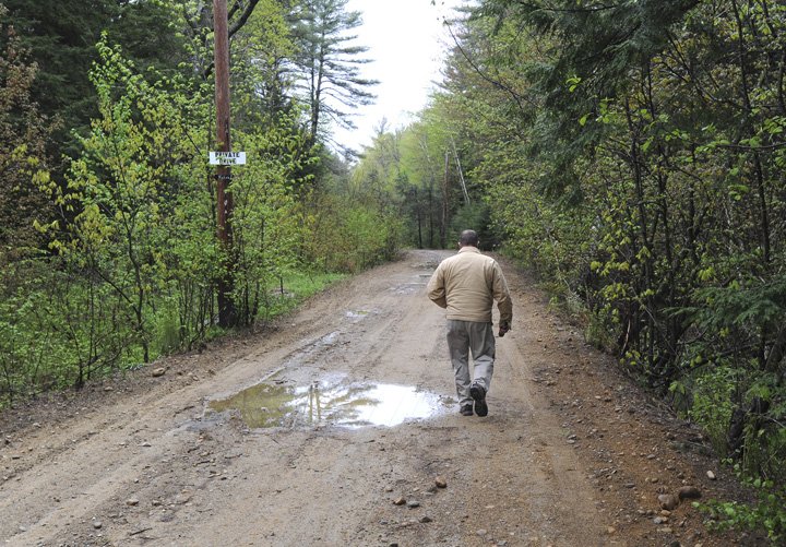 A member of the South Berwick Police Deptartment walks down a dirt road at 100 Dennett Road in South Berwick where the body of a young boy was found on Saturday.