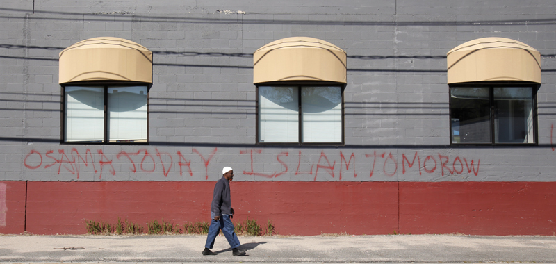 Jirde Mohamed walks past the front of a mosque on Anderson Street in Portland today where someone spraypainted graffiti on the wall in the wake of Osama Bin Laden's death. Bin Laden and Islam are not the same thing, said Mohammed, a member of the mosque who has lived in Portland 10 years.
