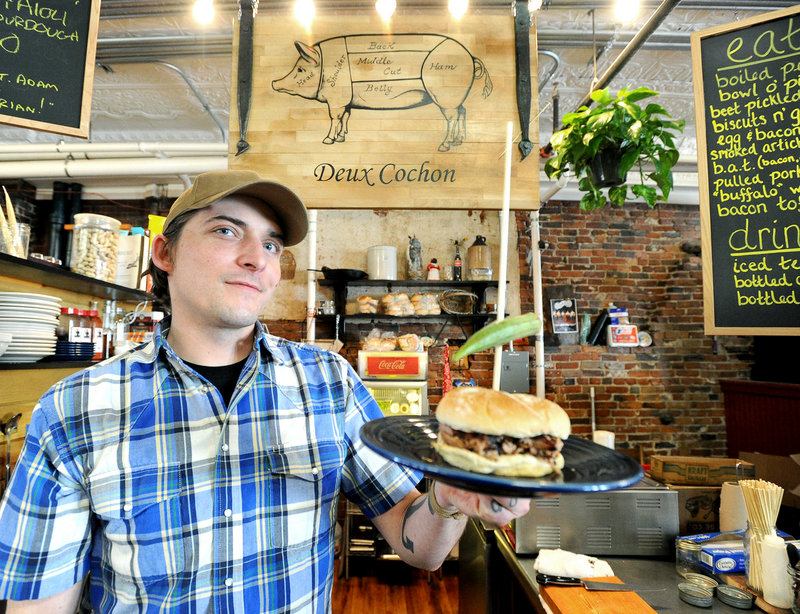 Adam Alfter, owner and chef, with a pulled pork sandwich at Deux Cochon in the Public Market House in Portland.
