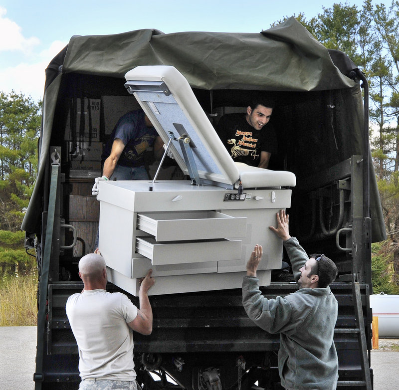 A donated examination table is hoisted into an Army truck by members of the 716 Engineers Battalion and volunteers for Partners for World Health as the group packs donated medical supplies and equipment for shipment to Haiti.