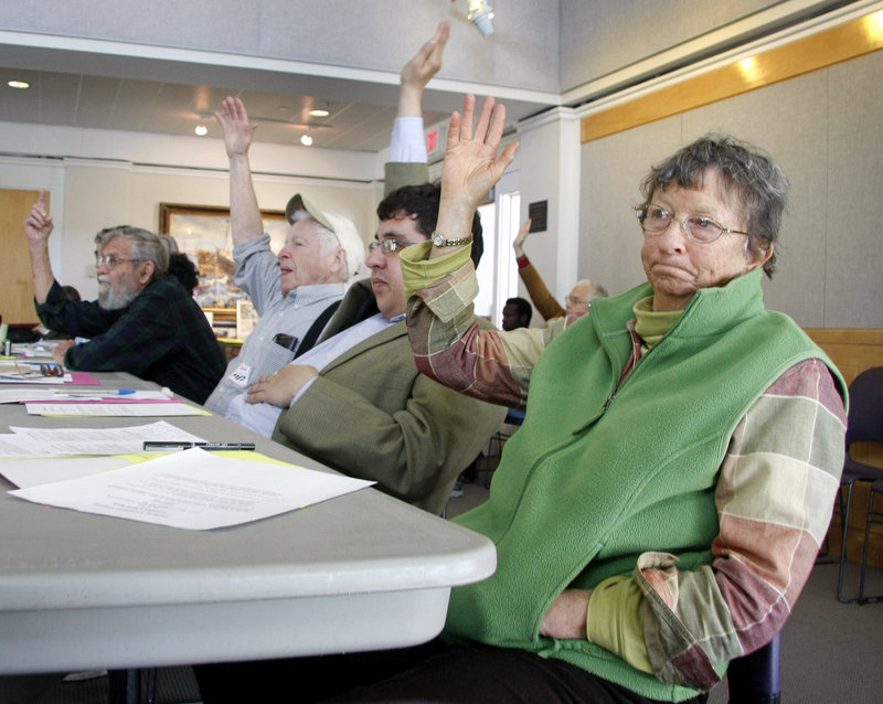 Lynne Harwood of Anson, right, joins fellow Maine Green Independent Party members Patrick Banks of Portland and Fred Dolgon of Old Orchard Beach as they vote on an energy amendment during the party’s annual statewide convention Sunday in Brunswick.