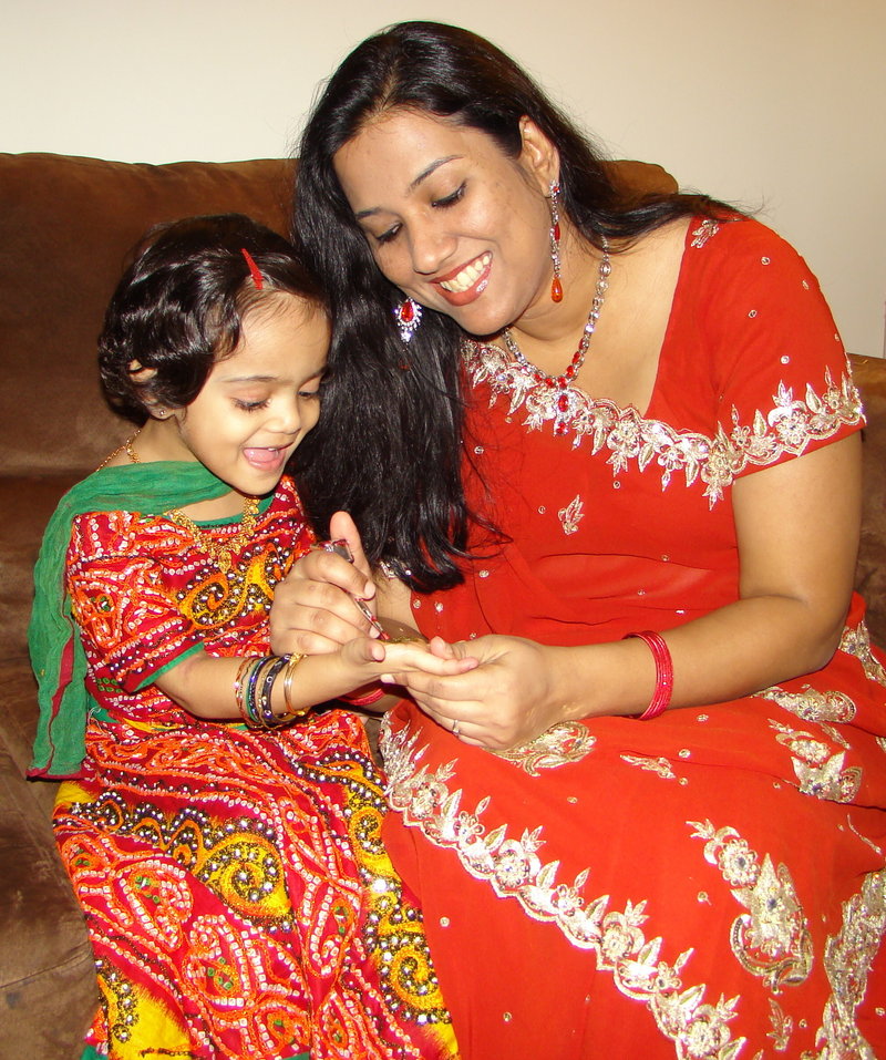 Sabina Naik paints henna onto her daughter Sarah Girach’s hand. Hand painting and bindi forehead painting will be offered during the festival.