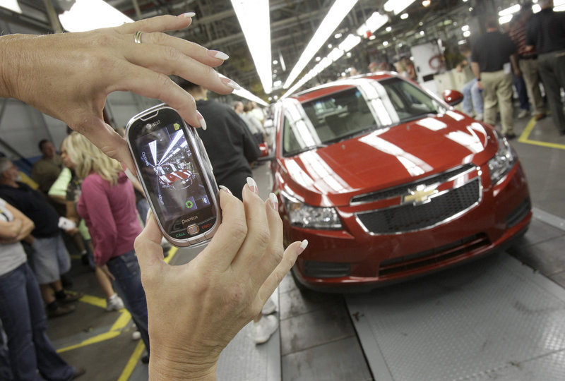 An auto worker photographs the first Chevrolet Cruze compact sedanproduced last September at the GM factory in Lordstown, Ohio. Small vehicles were big sellers in April.