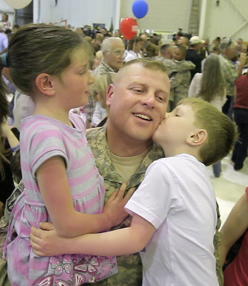 Sgt. Keith Kelly of Medway is greeted by his son Connor, 4, and his daughter Abigail, 6, after a ceremony Tuesday in Manchester, N.H., to welcome the 94th Military Police Company home from Iraq.