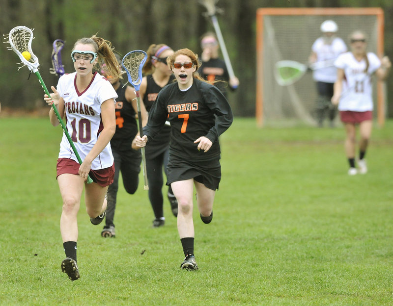 Michelle Giroux of Thornton Academy races down the field Wednesday after coming up with a ground ball during the 15-1 victory against Biddeford in a schoolgirl lacrosse game at Saco. Danielle MacDonald of the Tigers gives chase. The Golden Trojans improved their record to 3-1. Biddeford is 0-3.