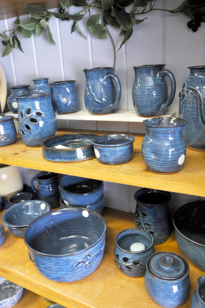 Wheel-thrown stoneware made by Joanne Kenyon is arranged on shelves.