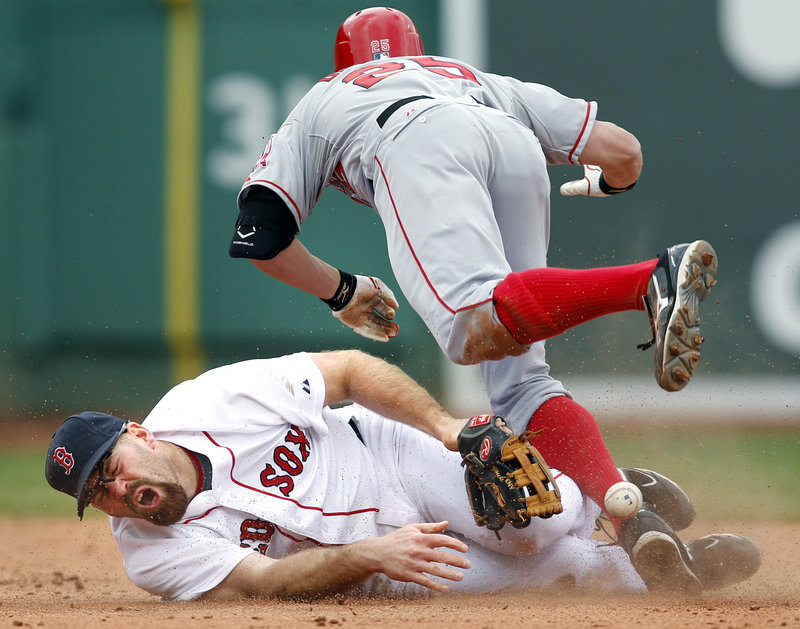 Kevin Youkilis of the Red Sox lies on the ground after colliding Thursday with Peter Bourjos of the Los Angeles Angels, who singled and moved to second when the base was uncovered. Youkilis had raced over to cover. Bourjos continued on to third.
