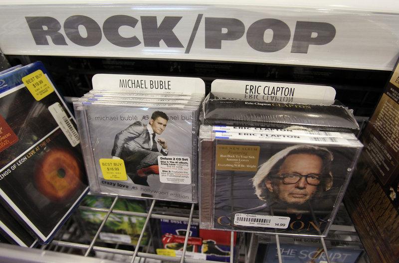 CDs by Eric Clapton and Michael Buble sit in a bin Friday at Best Buy in Mountain View, Calif. A 10-year battle with piracy has devastated the recording industry, and observers wonder if Warner Music’s sale shows seller smarts or buyer brilliance.