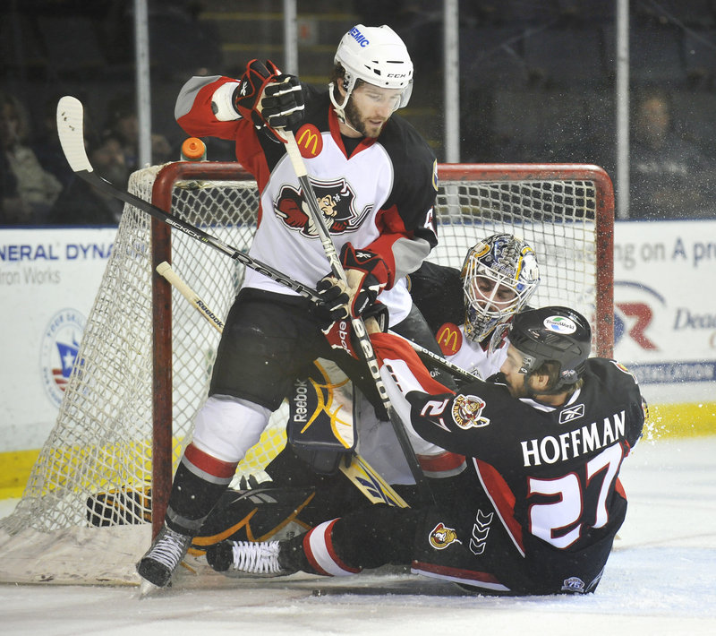 Binghamton s Mike Hoffman slides into Portland goalie Jhonas Enroth after being knocked to the ice by Portland s Brian O Haney on Friday night.
