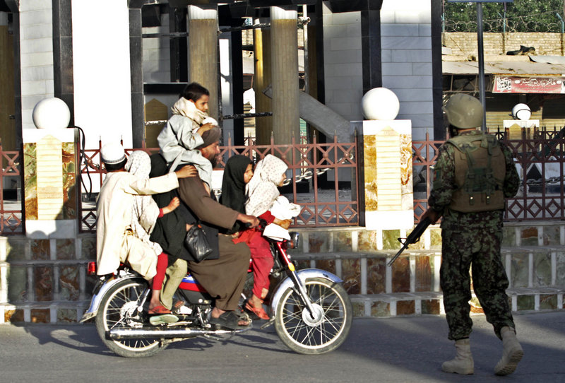 An Afghan security officer checks a bike carrying seven passengers after gunmen launched an attack on the governor' s compound in Kandahar province, south of Kabul, Afghanistan, on Saturday.