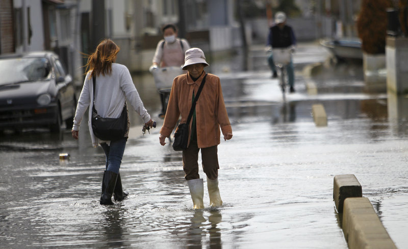 Residents navigate a flooded street last week in Ishinomaki, Miyagi Prefecture, Japan. A part of the city sunk nearly 2 feet 7 inches following the March 11 earthquake and tsunami, meaning neighborhoods are flooded twice a day, during high tide. Scientists say the new conditions are permanent.