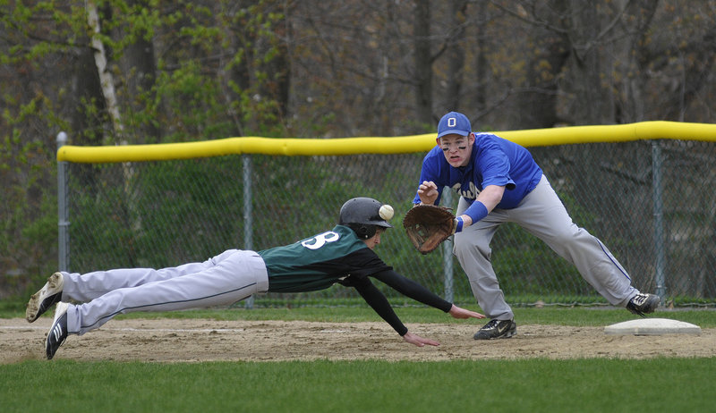Joey Schnier of Waynflete dives safely back into first base as Jason Dutton of Old Orchard Beach fields the pickoff throw Monday in Portland. Waynflete won, 6-4.