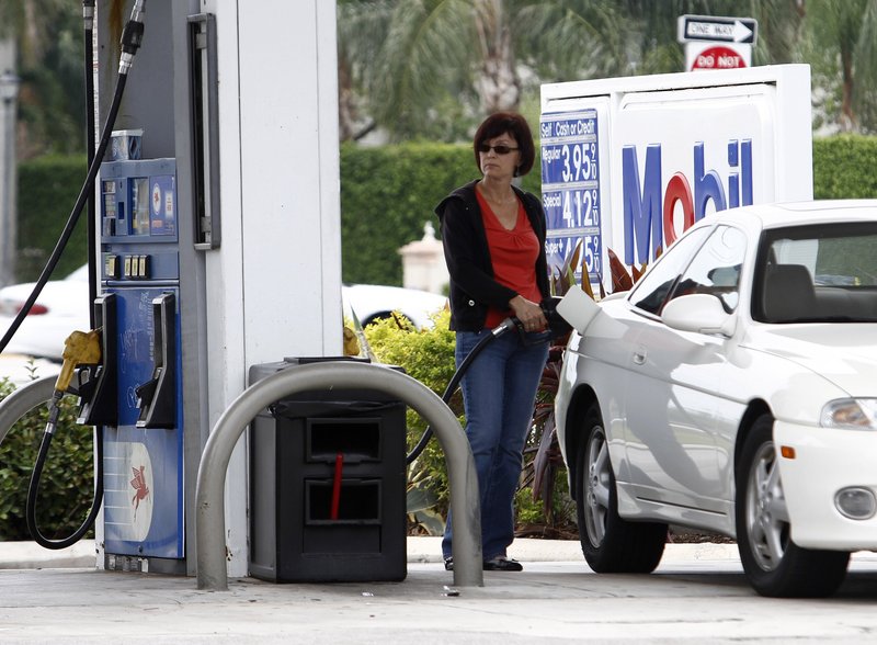 A motorist fills her gas tank at a Mobil gas station in Pembroke Pines, Fla., where the price of regular gas was near $4 a gallon last week. Retail gas prices are not falling immediately, despite the sharp drop in the cost of crude oil.
