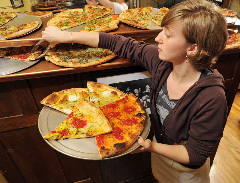 Jillian Smitherman puts pizza slices on a warming pan at the Otto pizza shop on Congress Street in Portland on Tuesday.