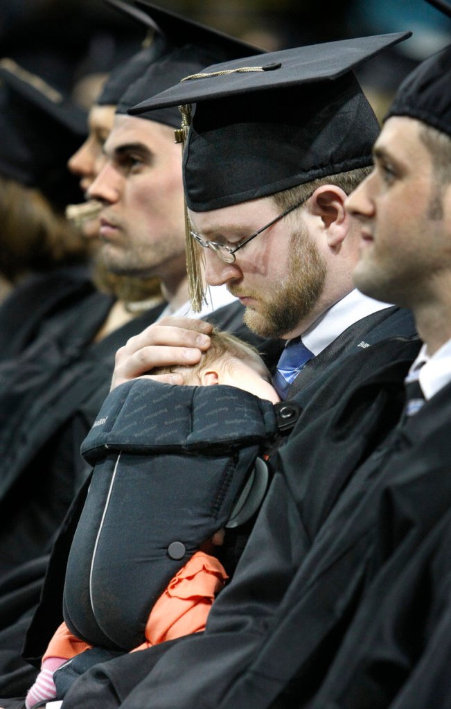 Patrick Kelleher of Lisbon Falls holds his 5-week-old sleeping daughter, Cadence, as he waits to receive his diploma at USM’s commencement Saturday.