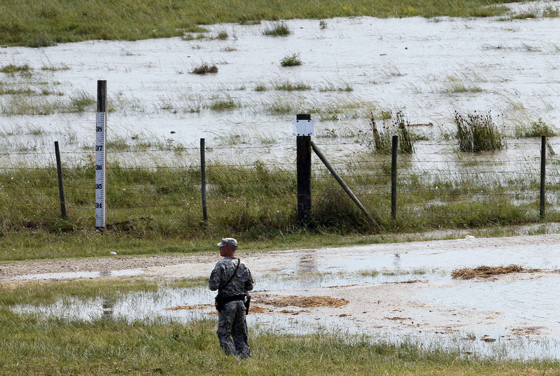 A member of the Louisiana National Guard watches as water diverted from the Mississippi River through the Morganza Spillway begins to fill a pasture in Morganza, La., Saturday.