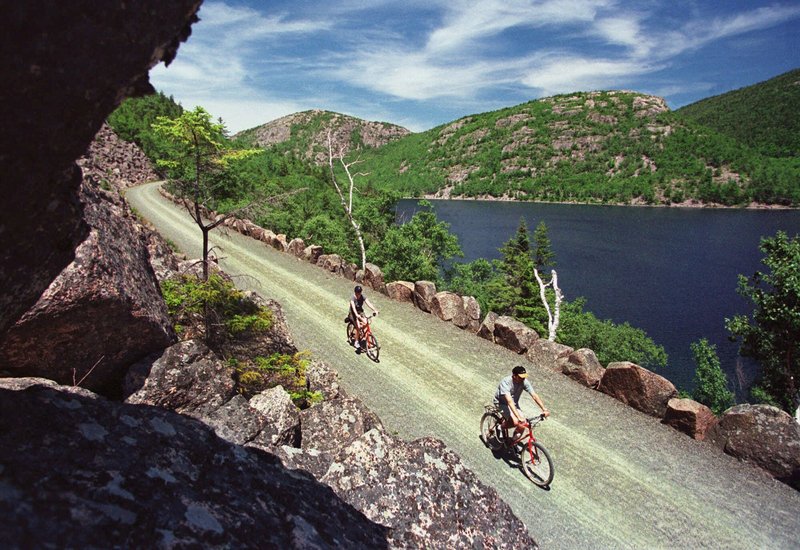 Bicyclists glide past a vista overlooking Jordan Pond and the Bubbles Mountains on a carriage road at Acadia National Park, near Bar Harbor.