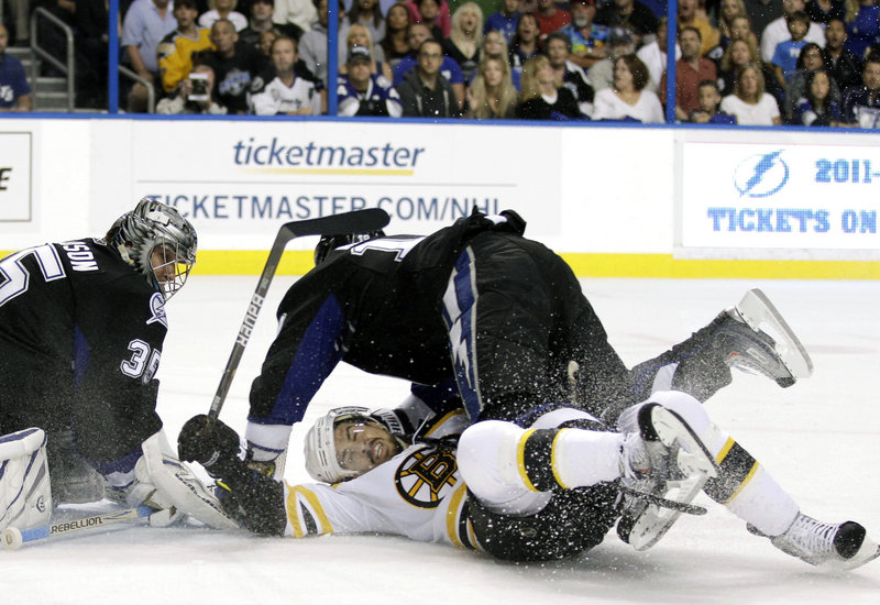 Dominic Moore of the Tampa Bay Lightning lands atop Chris Kelly of Boston in front of Lightning goalie Dwayne Roloson during the Bruins’ 2-0 victory Thursday night.